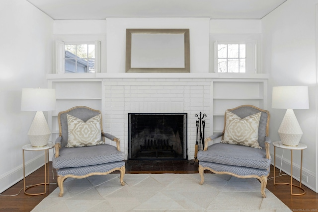 sitting room featuring a brick fireplace, wood finished floors, and baseboards