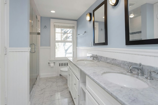 full bathroom featuring marble finish floor, a wainscoted wall, a sink, and a shower stall