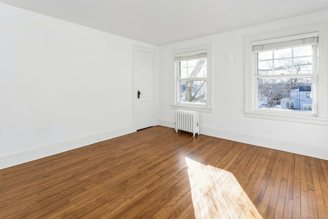 spare room with radiator heating unit, baseboards, and wood finished floors