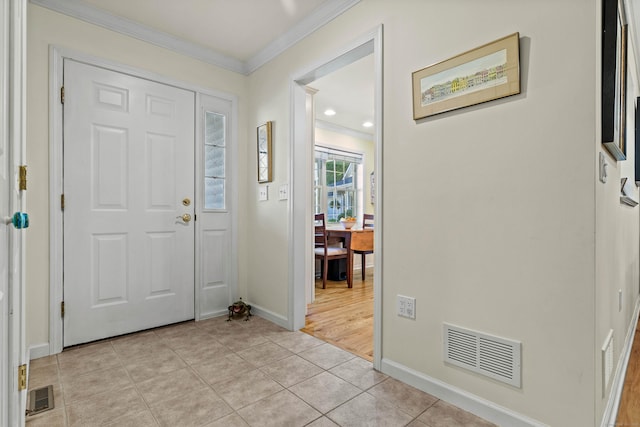 foyer with light tile patterned floors and crown molding