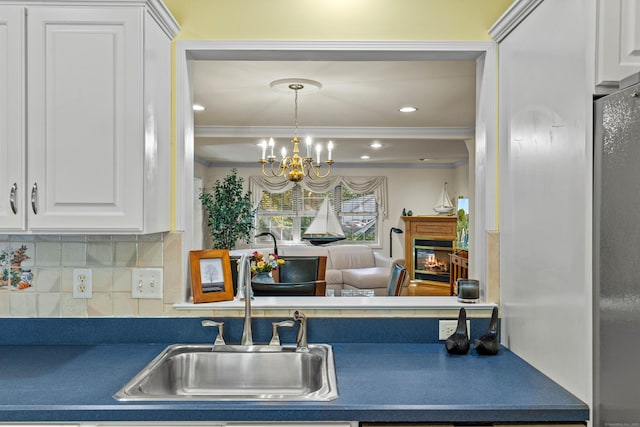 kitchen with ornamental molding, sink, white cabinetry, and backsplash