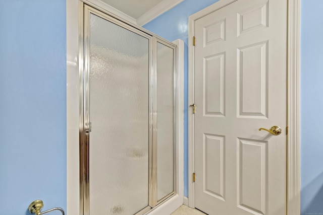 bathroom with ornamental molding and an enclosed shower