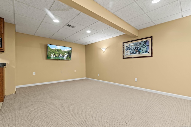 basement featuring a paneled ceiling and carpet flooring