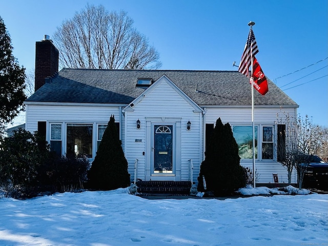 cape cod-style house featuring a chimney and roof with shingles