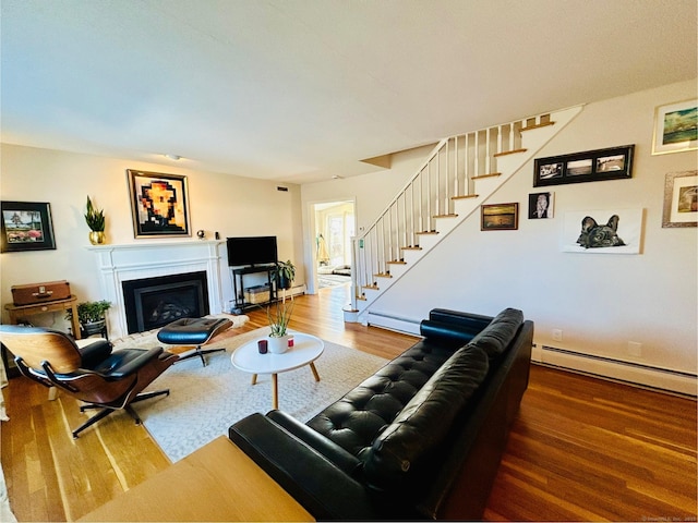 living area with a fireplace, a baseboard radiator, stairway, a baseboard heating unit, and wood finished floors