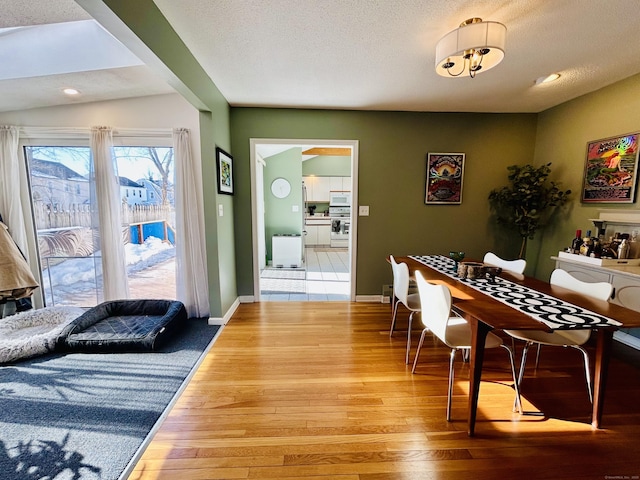 dining space with a textured ceiling, hardwood / wood-style floors, and baseboards