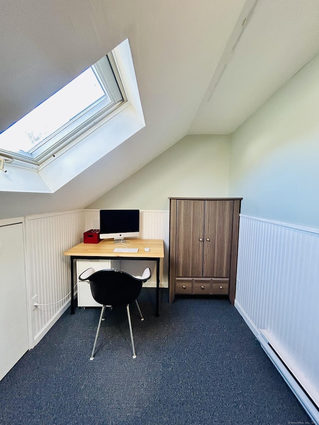 unfurnished office with a baseboard heating unit, vaulted ceiling with skylight, a wainscoted wall, and dark carpet