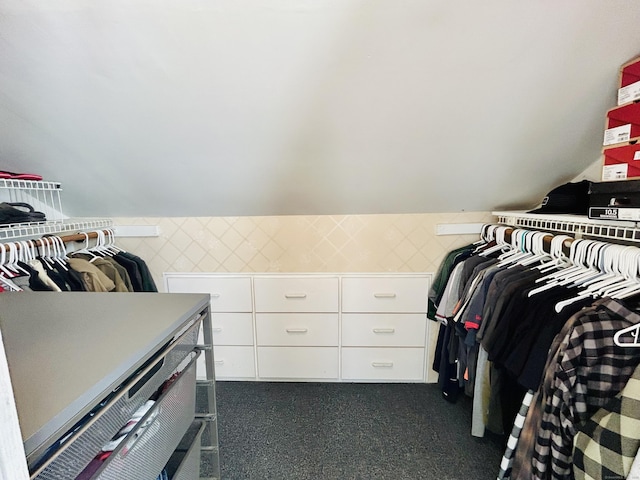 walk in closet with dark colored carpet and lofted ceiling