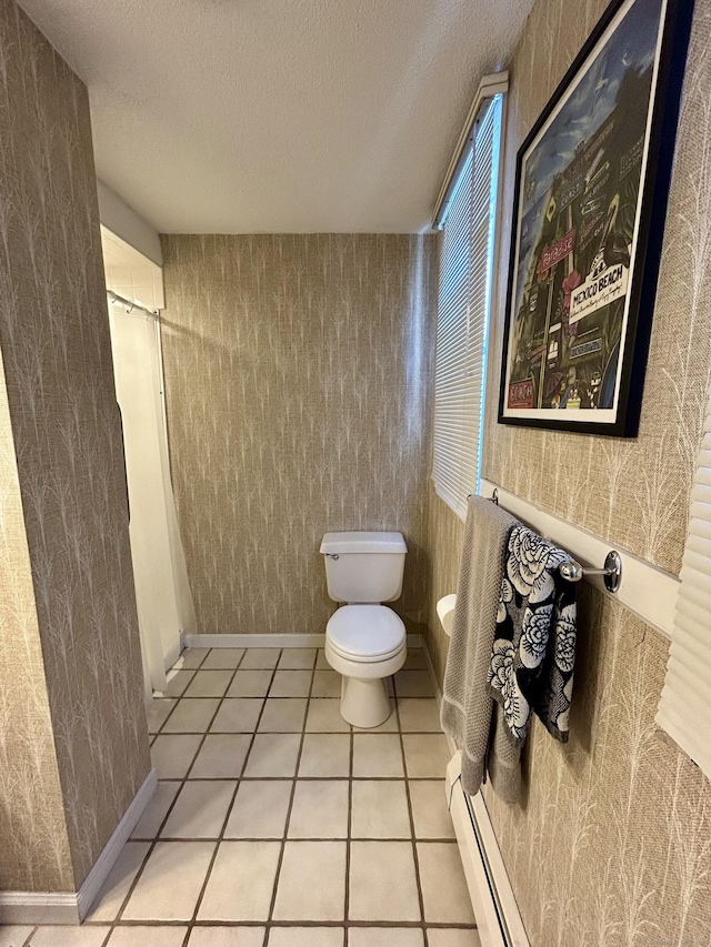 full bath with a shower with shower curtain, toilet, tile patterned floors, a textured ceiling, and a baseboard heating unit