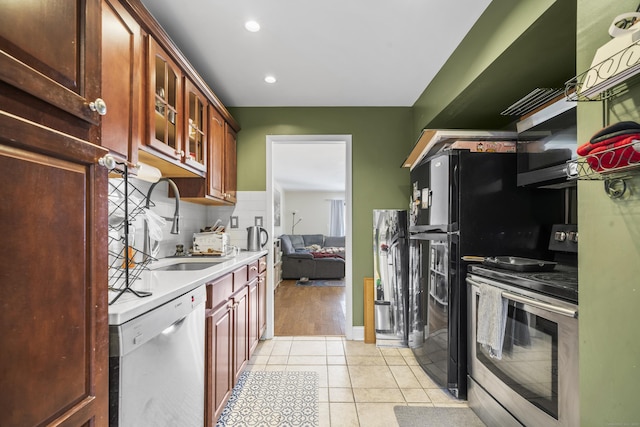 kitchen featuring appliances with stainless steel finishes, light tile patterned flooring, sink, and tasteful backsplash