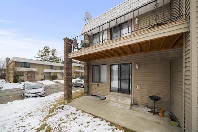 snow covered patio featuring a balcony