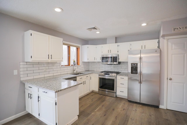 kitchen with visible vents, white cabinets, appliances with stainless steel finishes, light stone countertops, and a sink