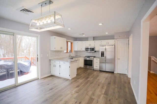 kitchen with visible vents, appliances with stainless steel finishes, a sink, white cabinetry, and backsplash