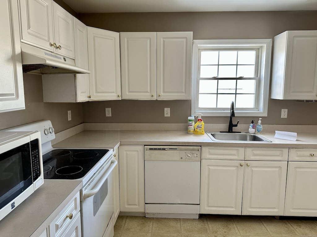 kitchen with electric range, white dishwasher, white cabinets, and sink