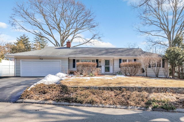 ranch-style house with a garage, fence, a chimney, and aphalt driveway