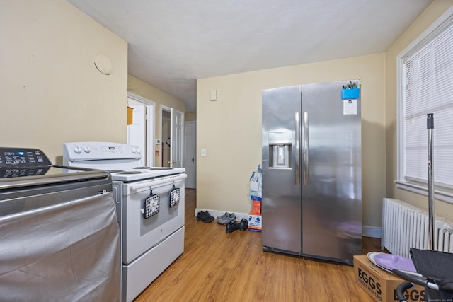 kitchen with light hardwood / wood-style flooring, radiator heating unit, washer / dryer, stainless steel refrigerator with ice dispenser, and electric stove