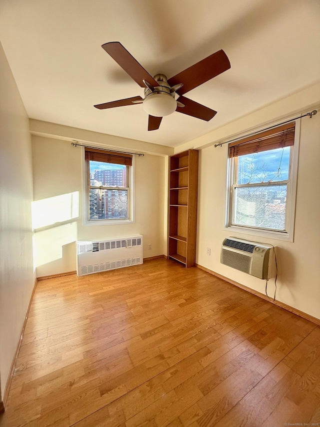 spare room with a wall mounted air conditioner, radiator heating unit, and light hardwood / wood-style floors