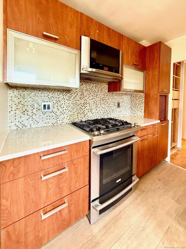 kitchen with appliances with stainless steel finishes, light hardwood / wood-style flooring, and tasteful backsplash