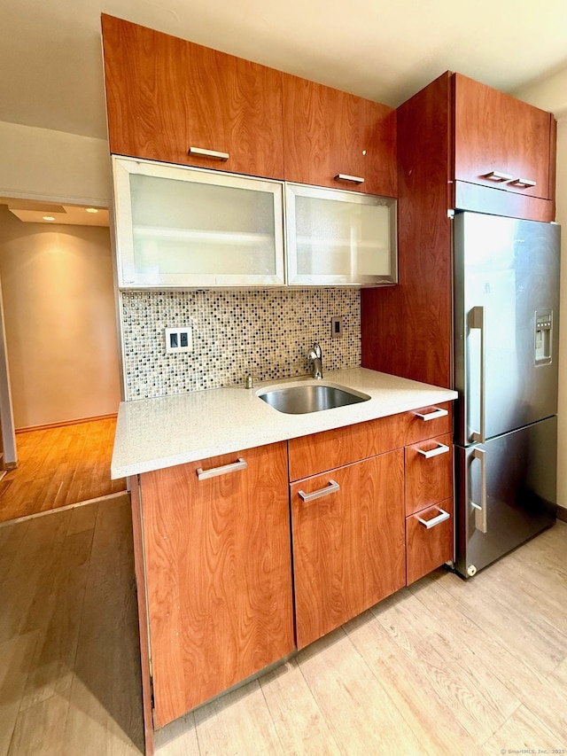 kitchen featuring light hardwood / wood-style flooring, sink, stainless steel fridge, and tasteful backsplash