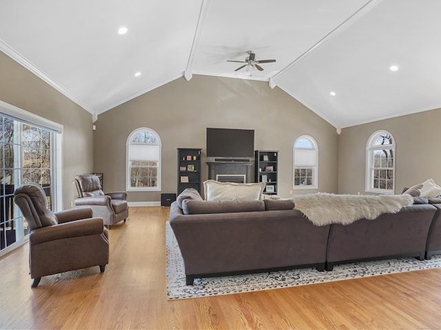 living area with ceiling fan, light wood-style flooring, ornamental molding, and vaulted ceiling