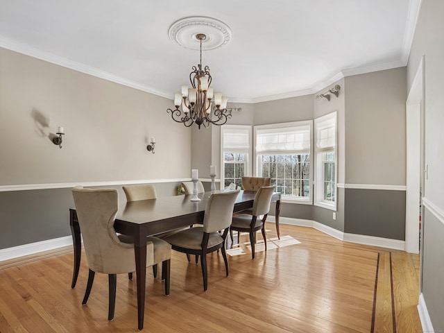 dining area featuring light wood-style floors, baseboards, crown molding, and an inviting chandelier