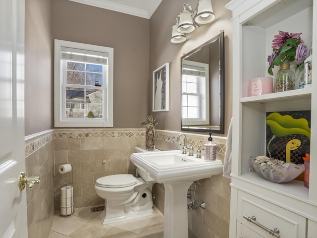 bathroom featuring ornamental molding, wainscoting, toilet, and tile patterned floors