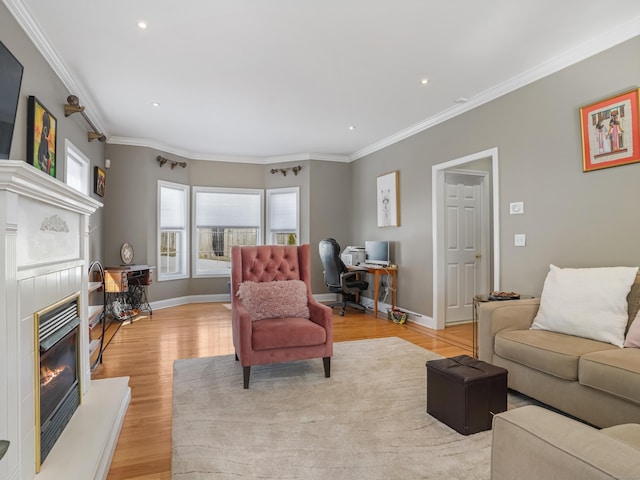 living room with a glass covered fireplace, baseboards, crown molding, and light wood finished floors