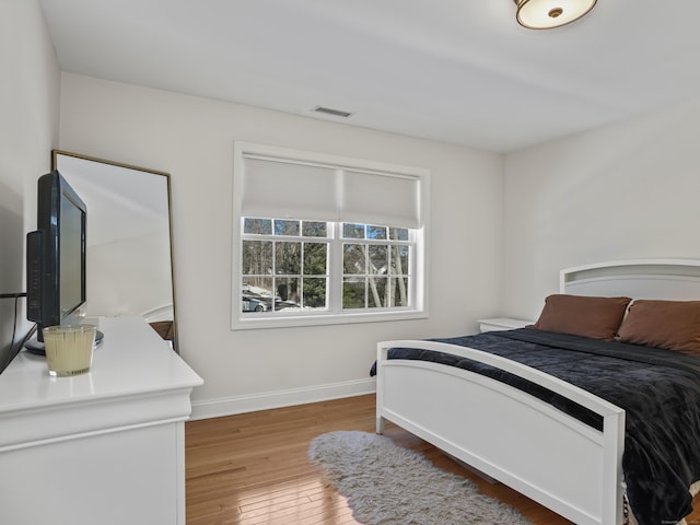 bedroom featuring visible vents, baseboards, and hardwood / wood-style floors