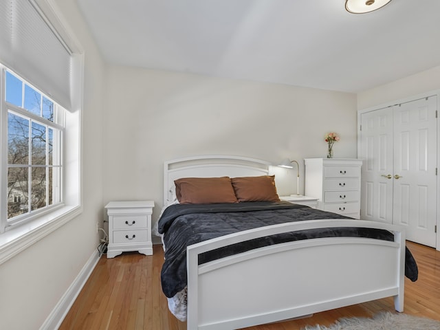 bedroom with a closet, baseboards, and wood finished floors