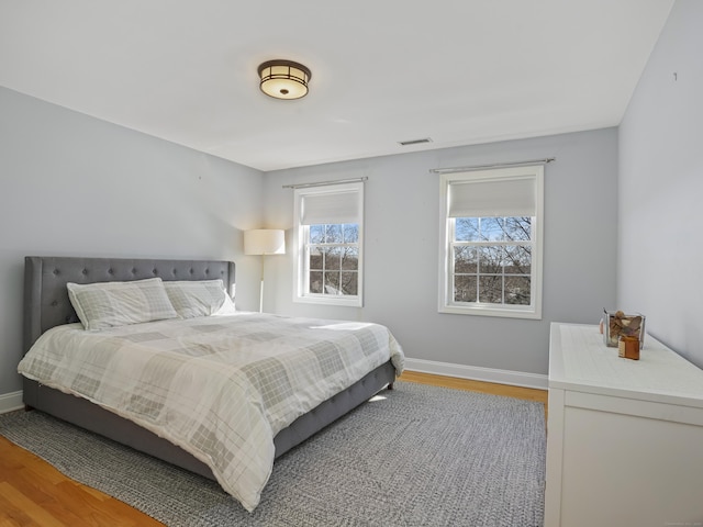 bedroom featuring baseboards, visible vents, and wood finished floors