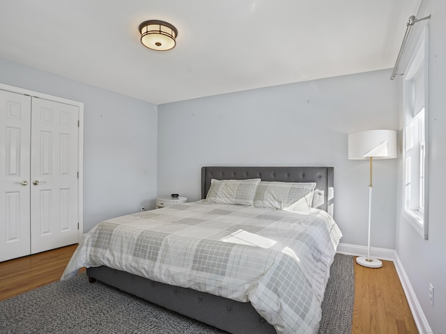 bedroom with a closet, wood finished floors, and baseboards