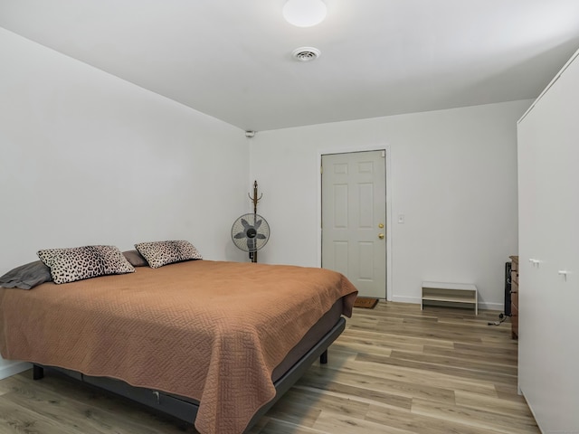 bedroom featuring visible vents, light wood-style flooring, and baseboards