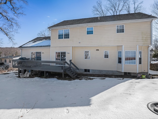 snow covered back of property featuring central AC unit and a wooden deck