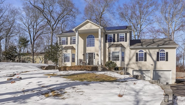 view of front facade featuring a garage, solar panels, and driveway