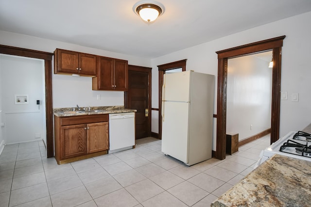 kitchen with white appliances, light stone countertops, light tile patterned flooring, and sink