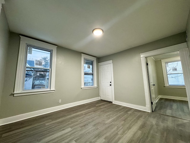 unfurnished bedroom with multiple windows, a closet, and hardwood / wood-style flooring