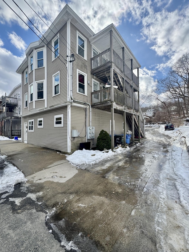 snow covered property with stairs and a balcony