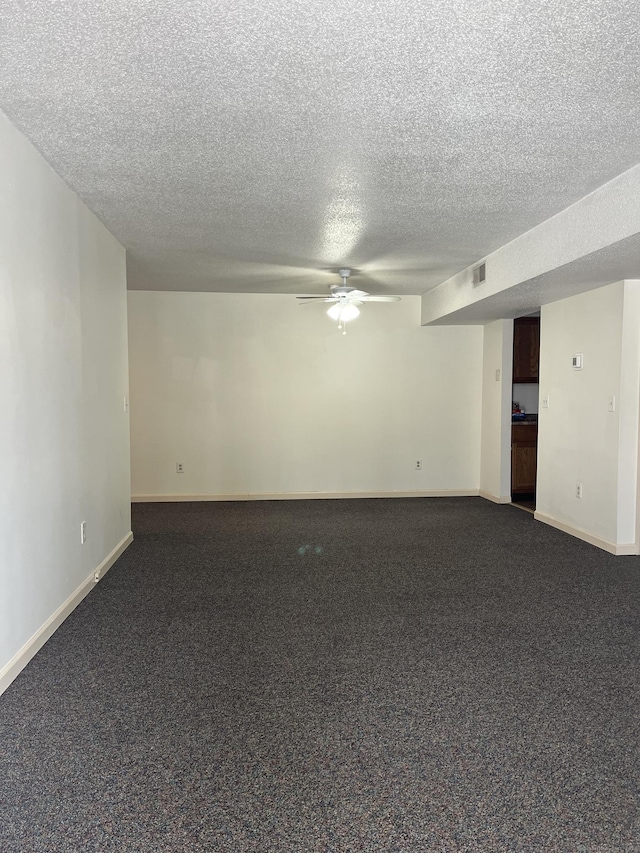 empty room featuring visible vents, dark carpet, ceiling fan, a textured ceiling, and baseboards