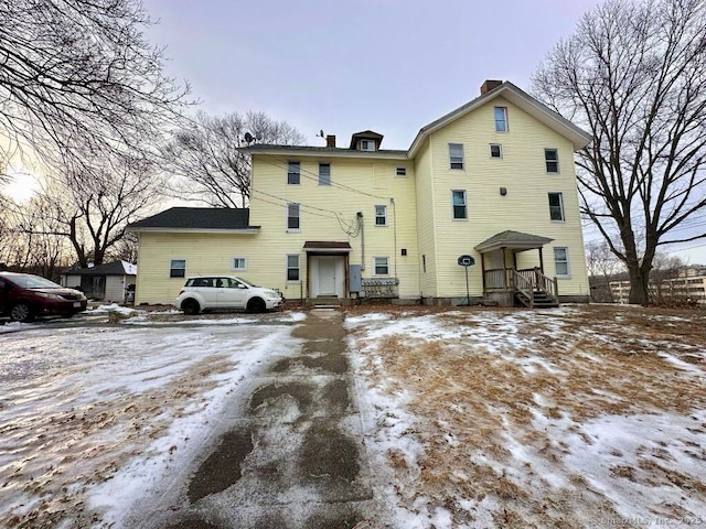 snow covered house featuring a chimney