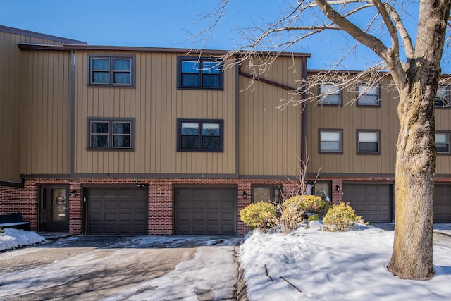 multi unit property featuring an attached garage and brick siding