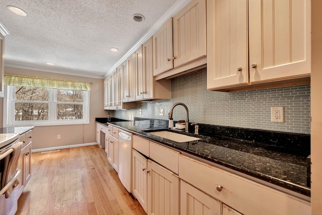 kitchen featuring a sink, light wood-type flooring, dishwasher, tasteful backsplash, and dark stone countertops