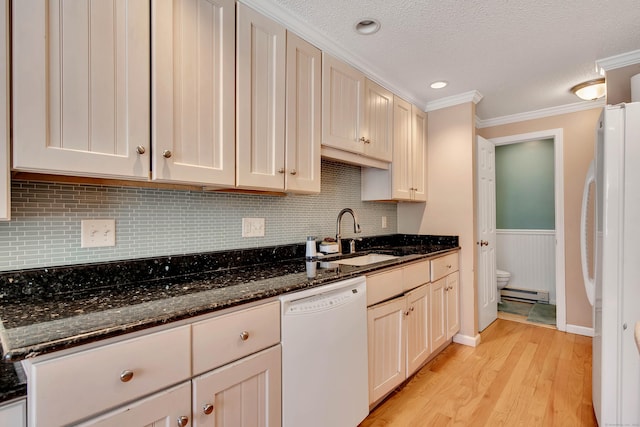 kitchen with white appliances, dark stone countertops, a sink, and a baseboard radiator