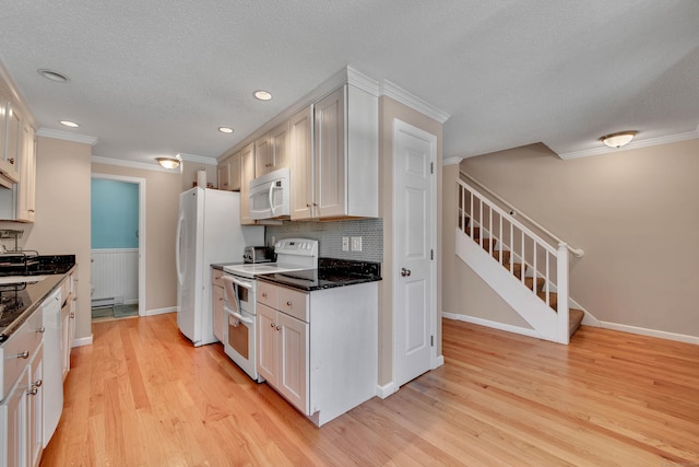 kitchen with white appliances, dark countertops, light wood-style flooring, crown molding, and white cabinetry