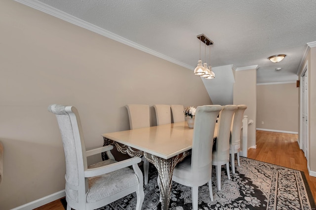 dining space with baseboards, a textured ceiling, ornamental molding, and wood finished floors