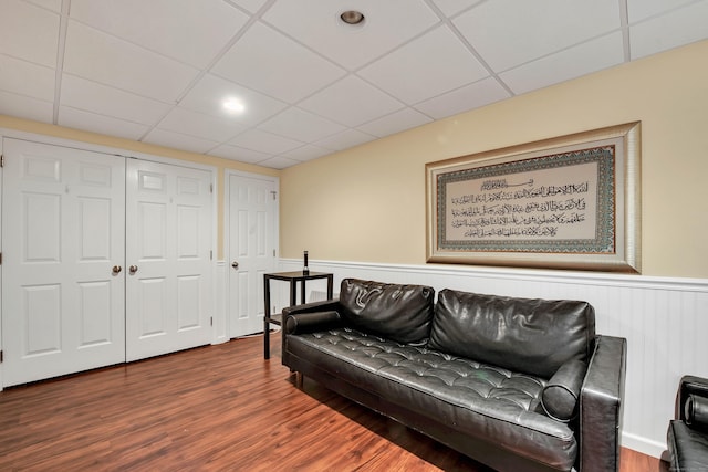 living area with a paneled ceiling, a wainscoted wall, and wood finished floors