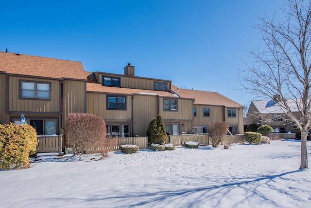 snow covered property with a chimney