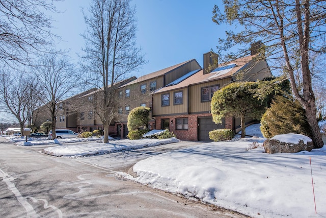 view of front of house with brick siding, driveway, a chimney, and an attached garage