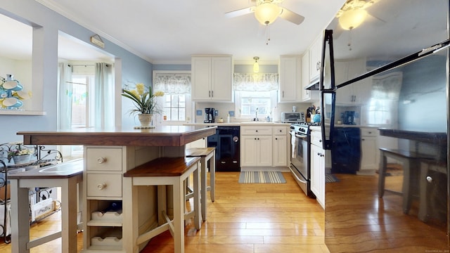 kitchen featuring sink, black dishwasher, white cabinetry, light hardwood / wood-style floors, and stainless steel range with gas cooktop