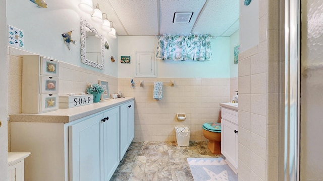 bathroom with tile walls, vanity, and toilet