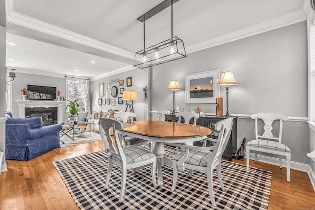 dining area featuring light wood-type flooring, a high end fireplace, and crown molding